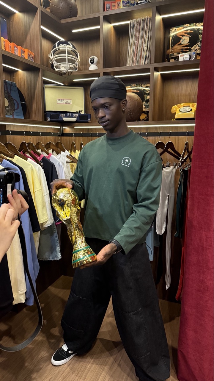 Deji in a green sweatshirt with a gold trophy